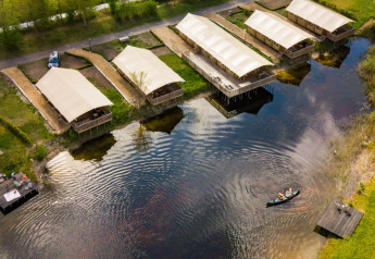 Vue aérienne des tentes safari près d’un lac au Holiday Park Eigen Wijze, Pays-Bas, avec un canoë.