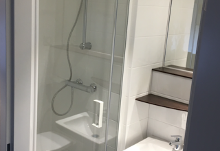 Petite salle de bain avec douche, lavabo, étagères et miroir dans une tente safari à Holiday park Eigen Wijze.