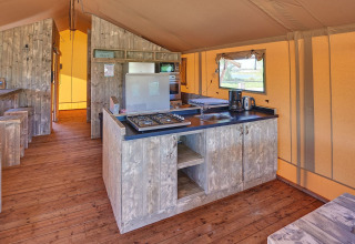 Interior de una tienda safari con cocina y electrodomésticos en Holiday park Eigen Wijze, Países Bajos.