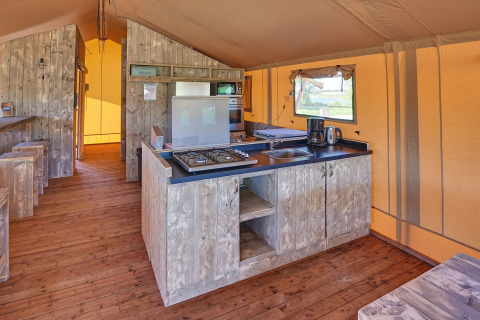 Keukeninrichting in een safaritent met houten vloer en apparatuur bij Holiday park Eigen Wijze, Nederland.