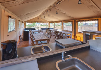 Indvendig udsigt fra gruppe-safaritelt på Holiday park Eigen Wijze med spiseborde og køkkenområde.