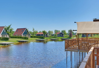 Vista su tende glamping e case vacanza presso un lago nel Holiday park Eigen Wijze nei Paesi Bassi, giornata soleggiata.