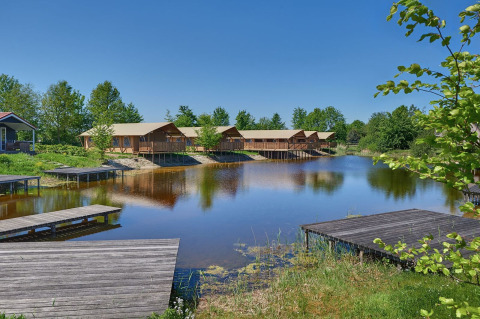 Tentes safari et quais en bois au bord d’un lac, Holiday park Eigen Wijze, Pays-Bas, sous ciel bleu.