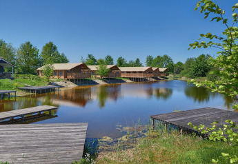 Safari telte og badebroer ved søen på Holiday park Eigen Wijze, Holland, under en klar blå himmel.