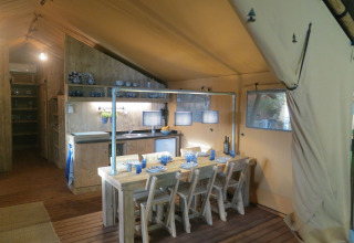 Vista interior de una tienda safari con cocina y comedor en Holiday Park Eigen Wijze, Países Bajos.