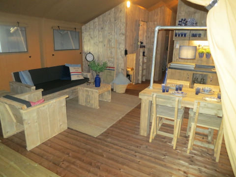 Intérieur de tente safari avec mobilier en bois, salon et salle à manger au Holiday park Eigen Wijze.