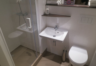 Salle de bain moderne dans une tente safari avec douche, lavabo et WC au Holiday park Eigen Wijze, Pays-Bas.