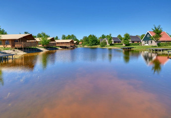 View of a tranquil lake with luxury glamping tents and cottages at Holiday park Eigen Wijze in the Netherlands.