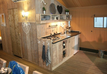 Wood-paneled kitchen inside a luxury safari tent at Holiday Park Eigen Wijze in the Netherlands.