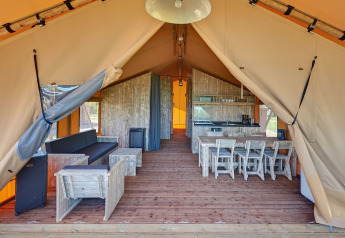 Vista interna di una tenda safari con mobili rustici in legno al Holiday park Eigen Wijze nei Paesi Bassi.