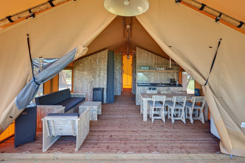Interior view of a safari tent with rustic wooden furniture at Holiday park Eigen Wijze in the Netherlands.