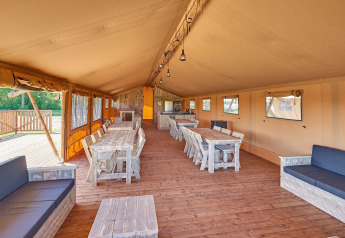 Interior view of a spacious safari group tent with wooden furniture at Holiday park Eigen Wijze, Netherlands.