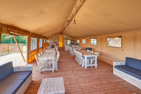 Interieur van een ruime safaritent voor groepen met houten meubilair op Holiday park Eigen Wijze, Nederland.
