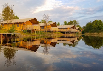 Safari and luxury glamping tents by a lake at Holiday park Eigen Wijze, Netherlands, surrounded by nature.