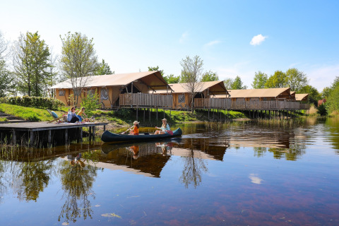 Familias disfrutan de una canoa en el lago junto a tiendas safari en Holiday park Eigen Wijze, Países Bajos.