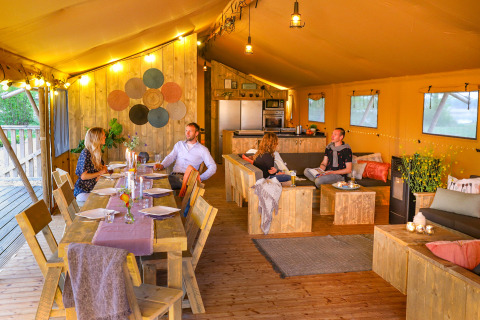 Quatre personnes dînent et se détendent dans une tente safari de luxe au Holiday park Eigen Wijze, Pays-Bas.