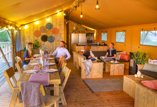 Quatre personnes dînent et se détendent dans une tente safari de luxe au Holiday park Eigen Wijze, Pays-Bas.