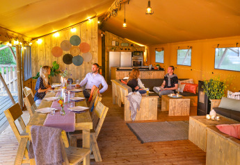 Cuatro personas cenan y se relajan en una tienda safari de lujo en Holiday park Eigen Wijze, Países Bajos.