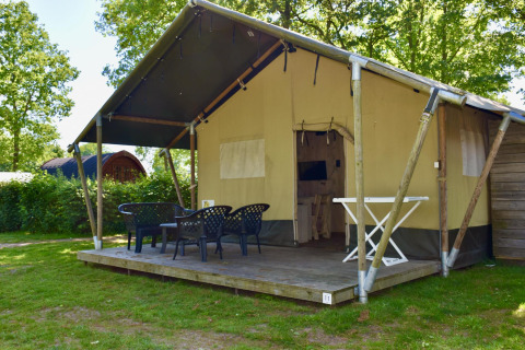 Tienda safari Comfort con terraza y sillas en Camping 't Veld, Países Bajos, rodeada de naturaleza.