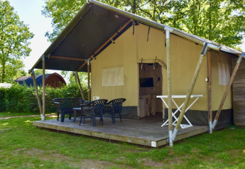 Comfort safari tent lodge with deck seating at Camping 't Veld in the Netherlands, surrounded by trees.