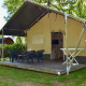 Komfortabel safaritelte-lodge med terrasse og stole på Camping 't Veld i Holland, omgivet af grøn natur.
