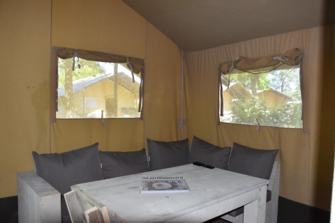 Interior de una tienda safari Comfort en Camping 't Veld, Países Bajos, con sofá en esquina.