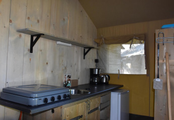 Kitchen area of the Comfort safari tent at Camping 't Veld in the Netherlands, featuring stove and fridge.
