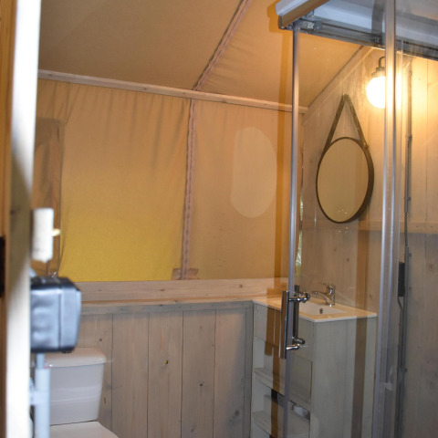 Modernes Badezimmer im Komfort-Safari-Zelt mit Holzverkleidung, Dusche, WC und Spiegel, Niederlande.