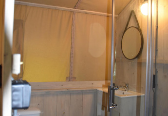 Baño de tienda safari Comfort en Camping 't Veld, Países Bajos, con madera, ducha y lavamanos.