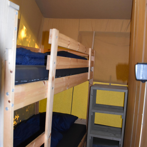 Habitación con litera de madera y estantería dentro de la Comfort safari tent en Camping 't Veld, Países Bajos.