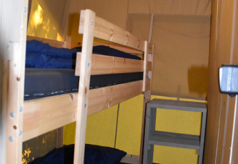 Room with wooden bunk bed and shelving unit inside Comfort safari tent at Camping 't Veld, Netherlands.