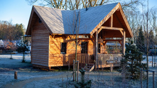 Gemütliche Holzlodge Heydehuis im Sandberghe, Niederlande, umgeben von frostiger Natur und Bäumen.
