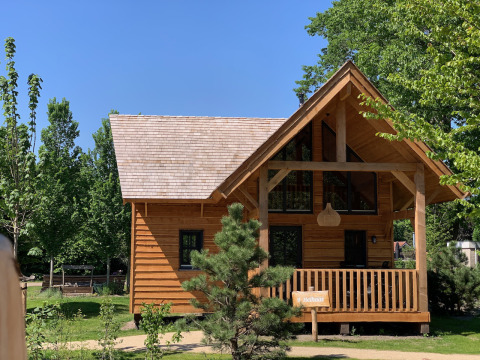 Wooden lodge named Heydehuis at Sandberghe in the Netherlands, surrounded by green trees and clear sky.