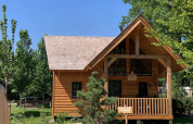 Holz-Lodge namens Heydehuis in Sandberghe, Niederlande, umgeben von grünen Bäumen und blauem Himmel.