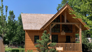 Wooden lodge named Heydehuis at Sandberghe in the Netherlands, surrounded by green trees and clear sky.