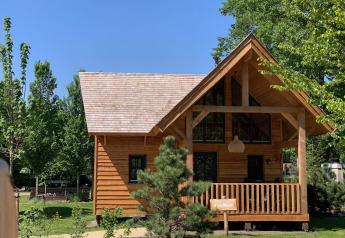 Holz-Lodge namens Heydehuis in Sandberghe, Niederlande, umgeben von grünen Bäumen und blauem Himmel.