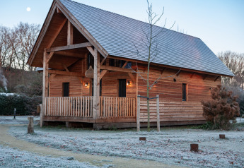 Houten lodge Heydehuis bij Sandberghe in Nederland, met rijm op het gras en een heldere hemel.