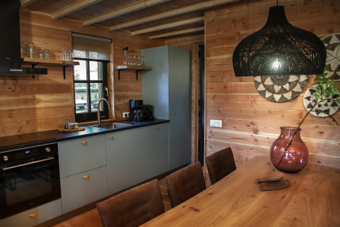 Modernes Glamping-Küchen- und Essbereich in Holzoptik mit stilvoller Beleuchtung und gemütlicher Atmosphäre.