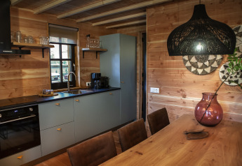 Cocina moderna y comedor glamping con paredes de madera, decoración elegante y luz cálida en Heydehuis.