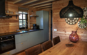 Cocina moderna y comedor glamping con paredes de madera, decoración elegante y luz cálida en Heydehuis.