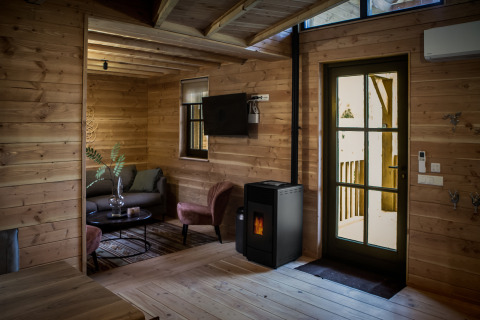 Vista interior del alojamiento glamping Heydehuis con paredes de madera, estufa de pellets y muebles modernos.