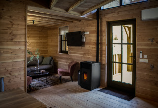 Vista interior del alojamiento glamping Heydehuis con paredes de madera, estufa de pellets y muebles modernos.