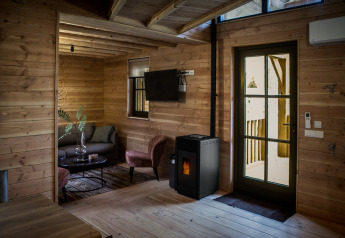 Vista interior del alojamiento glamping Heydehuis con paredes de madera, estufa de pellets y muebles modernos.