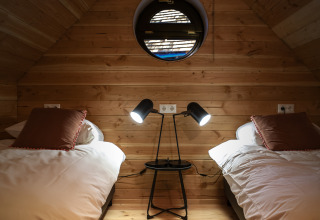 Cozy room at Heydehuis in Sandberghe, Netherlands, featuring two beds and a circular window.