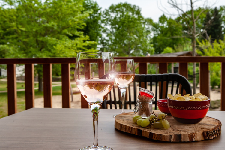 Dos copas de vino rosado, patatas fritas y uvas en una mesa exterior en el alojamiento glamping Heydehuis.