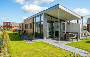 Modernes Tiny House in Tusken de Marren, Niederlande, mit großer Terrasse und gepflegtem Garten bei Sonne.