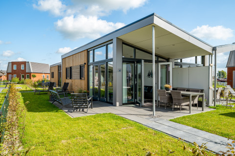 Modern tiny house at Tusken de Marren in the Netherlands, featuring a patio, garden, and large glass windows.