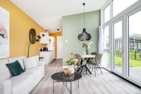 Modern living and dining area in Tiny House Knilles with large windows, pastel colors, and stylish decor.