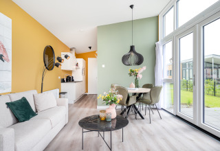 Modern living and dining area in Tiny House Knilles with large windows, pastel colors, and stylish decor.