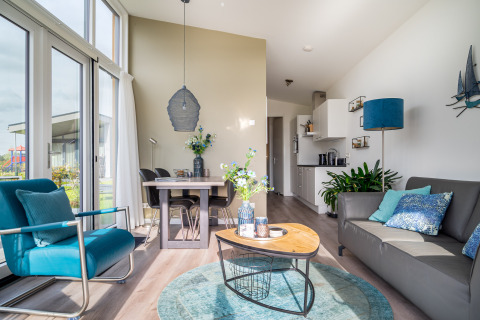 Bright, modern interior of tiny house Knilles at Tusken de Marren, Netherlands, featuring blue decor accents.